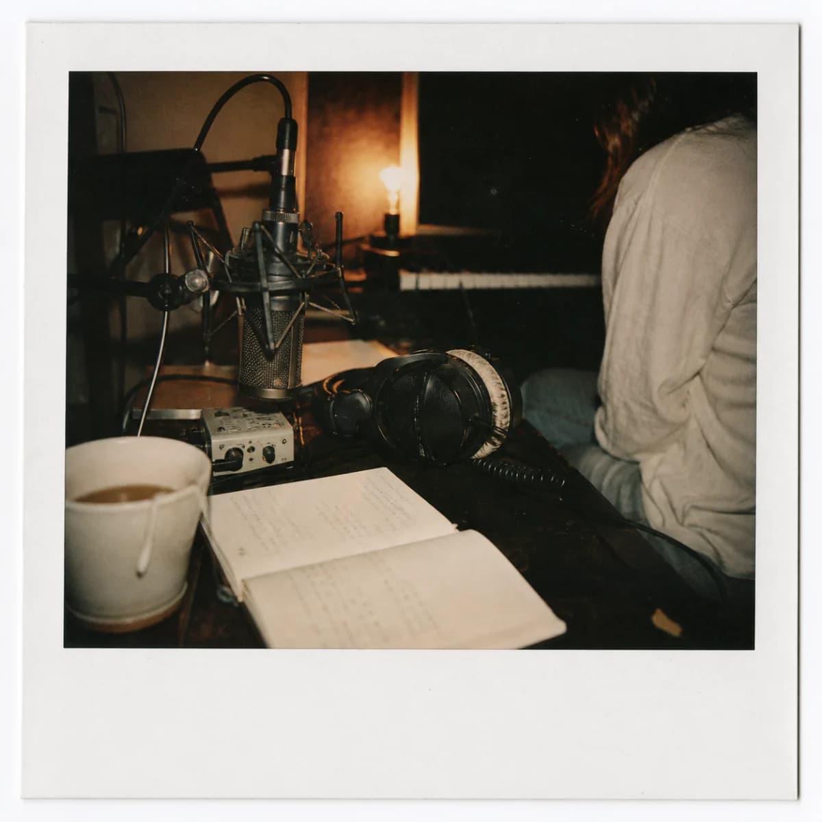 Polaroid aus einem nächtlichen Studio mit Mikrofon, Kopfhörern und Notizbuch.
